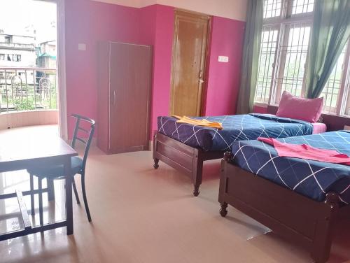 a bedroom with two beds and a table and a table at Hotel Suvika Inn in Guwahati