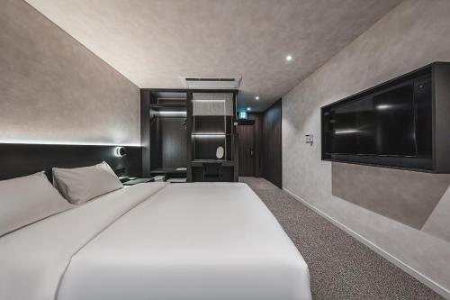a bedroom with a white bed and a flat screen tv at GOYOO INN & homes in Seoul