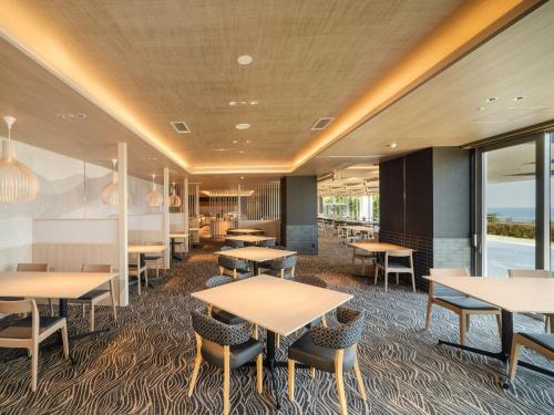 a dining room with tables and chairs and windows at KAMENOI HOTEL Awajishima in Awaji