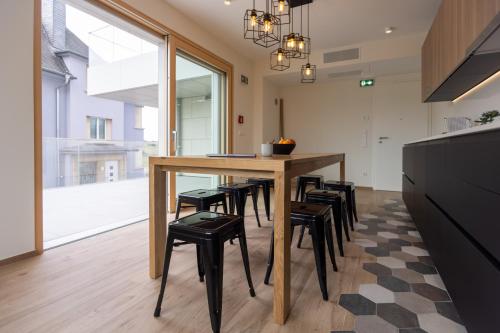 a dining room with a table and stools at Cessange House by Rentaroo in Luxembourg
