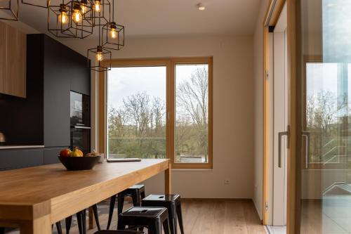 a kitchen with a wooden table and a large window at Cessange House by Rentaroo in Luxembourg