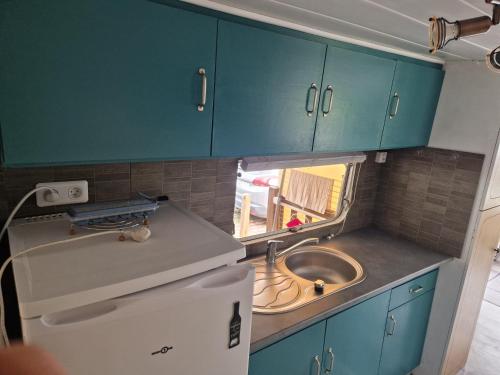 カンボ・レ・バンにあるMon Petit Mobil Homeの青いキャビネットとシンクを備えた小さなキッチン