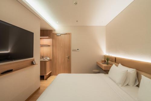 a hotel room with a bed and a flat screen tv at Nola Hotel in Ho Chi Minh City