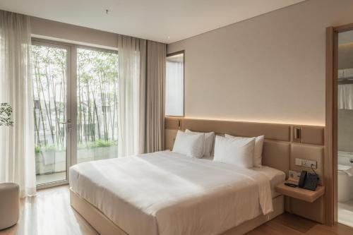 a bedroom with a large white bed and a window at Nola Hotel in Ho Chi Minh City