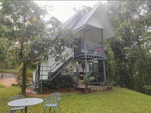 a white house with a balcony and a table and chairs at Poomala Holiday Village in Mulagunnathukāvu