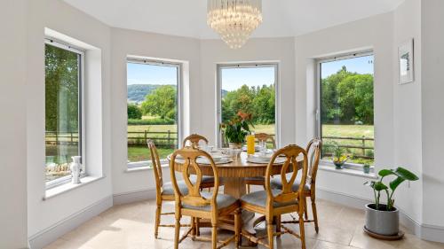 Great WitcombeにあるLeafield Houseのテーブルと椅子と窓のあるダイニングルーム