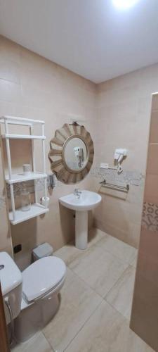 a bathroom with a toilet and a sink and a mirror at Apartamento Calle Real in Martos