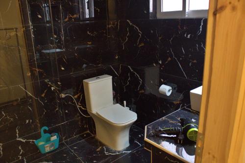 a black tiled bathroom with a white toilet in it at Aμvrosia Avramio Village - Fireplace, Free WiFi, Pet Friendly in Avramión