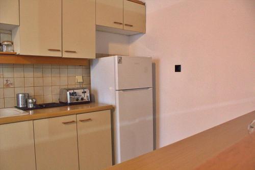 a kitchen with a white refrigerator and a sink at Aμvrosia Avramio Village - Fireplace, Free WiFi, Pet Friendly in Avramión