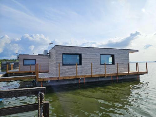 a tiny house on a dock on the water at Domki na wodzie, Apartamenty, Houseboat, Jezioro Bukowo, Mierzeja "Natura Dąbkowice 5G" in Dąbki