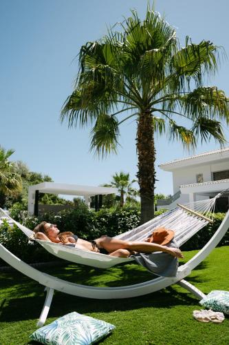two people laying in a hammock under a palm tree at M Mansion in Pefki Rhodes