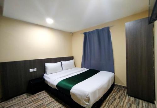 a bedroom with a large white bed with blue curtains at Fast Hotel Idaman Near To IIUM KL in Kuala Lumpur