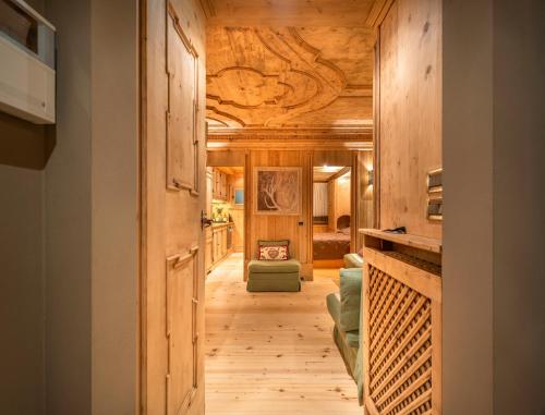 a hallway leading to a living room with wooden ceilings at Elegant Tablà with Garden R&R in Cortina dʼAmpezzo