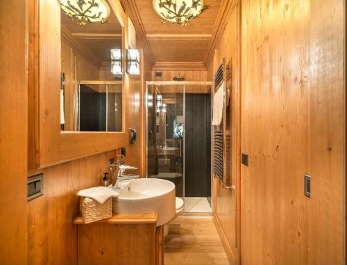 a bathroom with a white sink and a mirror at Elegant Tablà with Garden R&R in Cortina dʼAmpezzo