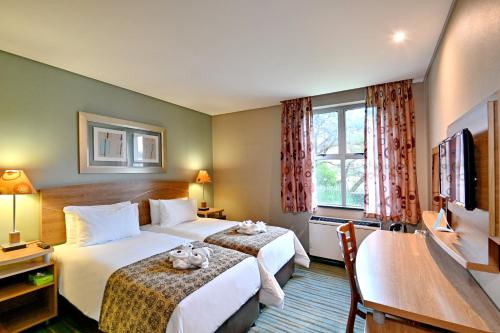 a hotel room with two beds and a television at Town Lodge Roodepoort in Roodepoort
