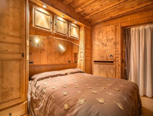 a bedroom with a bed in a wooden cabin at Elegant Tablà with Garden R&R in Cortina dʼAmpezzo