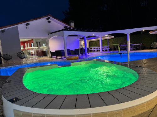 a swimming pool at night with a green pool at Villa Sany:10 Pers Maison 200m2 piscine , jacuzzi in Narrosse
