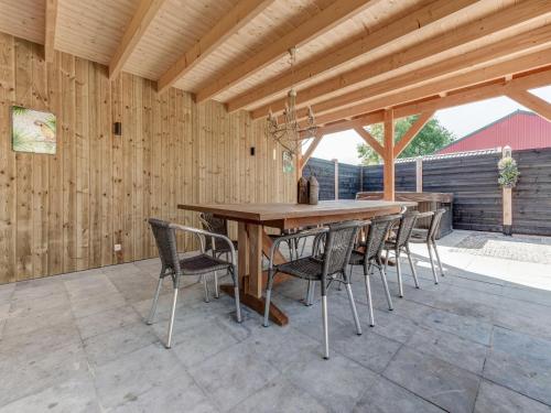 a wooden table and chairs on a patio at Stylish Farmhouse with Spa Tub in Kootstertille