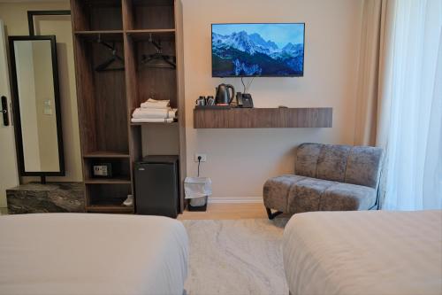 a bedroom with a bed and a chair and a tv at Hotel Valbor in Tropojë