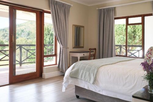 a bedroom with a bed and sliding glass doors at High Season Farm Luxury Cottages in Hermanus