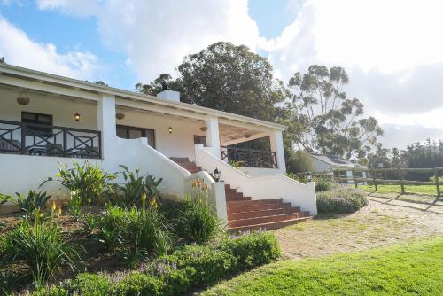 a white house with stairs in a yard at High Season Farm Luxury Cottages in Hermanus