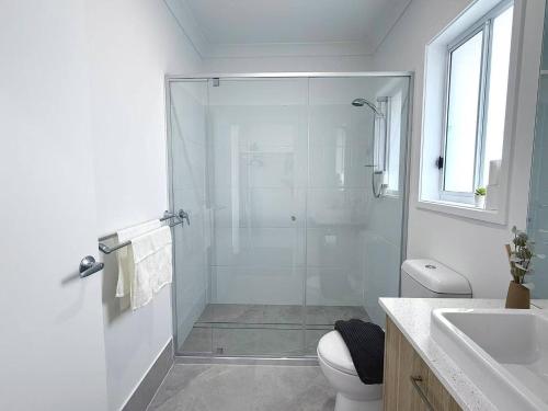 a bathroom with a shower and a toilet and a sink at Home Blanc - Brand New, Peaceful & Well Equipped in Ripley