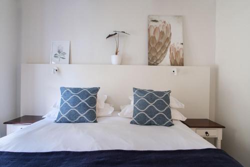 a bedroom with a bed with blue and white pillows at High Season Farm Luxury Cottages in Hermanus