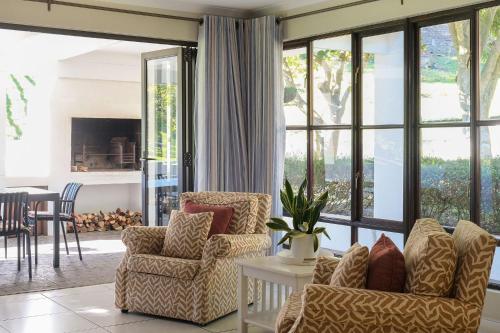 a living room with two chairs and a fireplace at High Season Farm Luxury Cottages in Hermanus