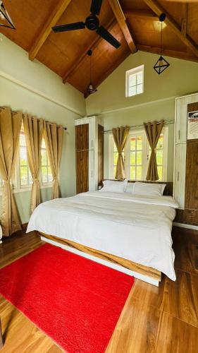 a bedroom with a large white bed with a red rug at Saanidhya Sunset View Villa in Mukteswar