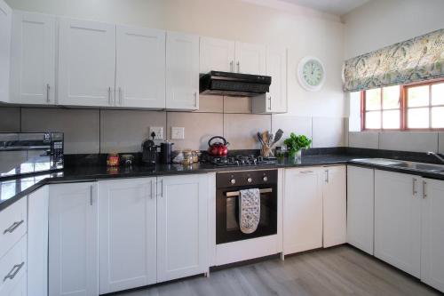 a kitchen with white cabinets and a stove top oven at High Season Farm Luxury Cottages in Hermanus