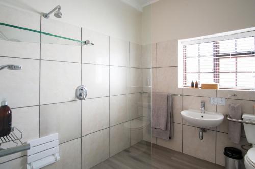 a white bathroom with a sink and a shower at High Season Farm Luxury Cottages in Hermanus