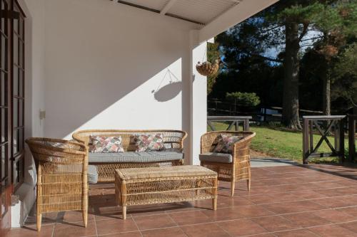 two wicker chairs and a couch on a porch at High Season Farm Luxury Cottages in Hermanus