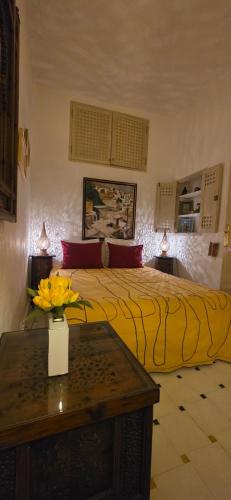 a bedroom with a bed with a vase of flowers on a table at Grande demeure de charme in Asilah