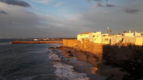 a group of white buildings on the shore of the water at Grande demeure de charme in Asilah