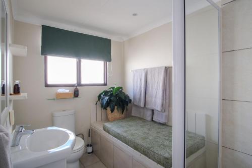 a bathroom with a sink and a toilet and a window at High Season Farm Luxury Cottages in Hermanus