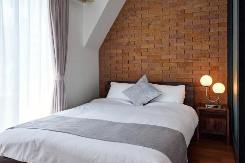 a bedroom with a white bed with a brick wall at R STAY Shiba in Tokyo