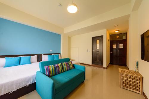 a bedroom with a large bed and a blue chair at Travel J in Taitung City