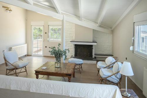 a living room with a table and chairs and a fireplace at Comfortable Villa - 2min from the Beach in Porto Rafti