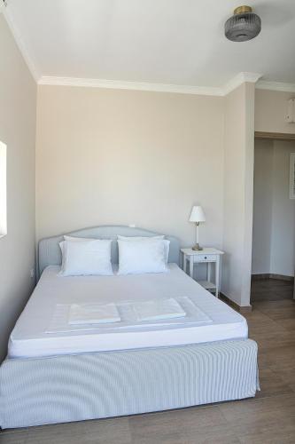 a large white bed in a room with a white wall at Comfortable Villa - 2min from the Beach in Porto Rafti