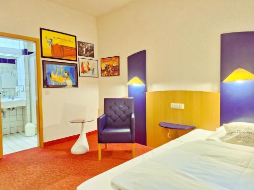 a hotel room with a bed and a chair at Retro - Art - Hotel Lünen in Lünen