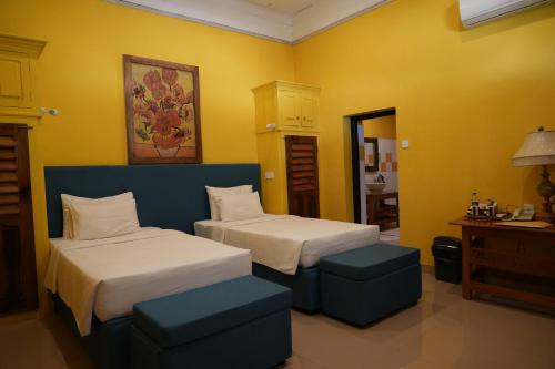 two beds in a room with yellow walls and yellow ceilings at Ella Planters Bungalow in Ella