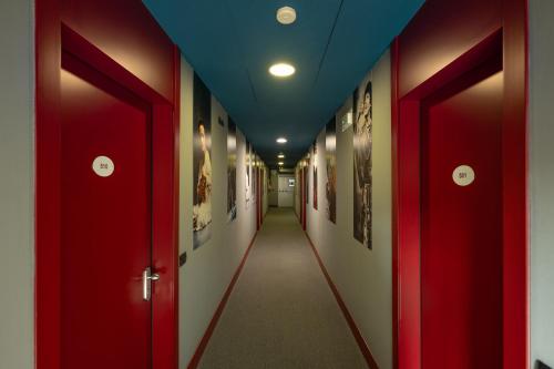 a corridor with red doors and a hallway with paintings at Romeo e Giulietta Residenze check-in presso Hotel Toscanini in Parma