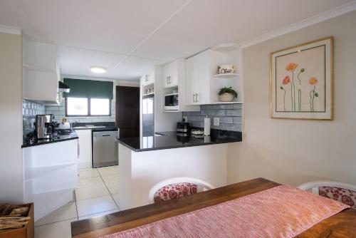 a kitchen with white cabinets and black counter tops at High Season Farm Luxury Cottages in Hermanus