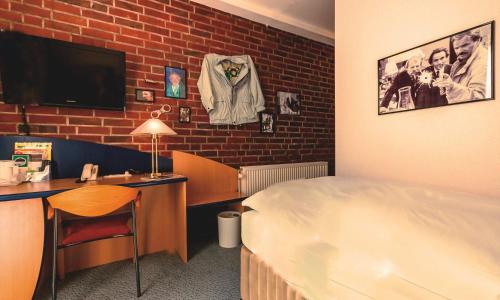 a hotel room with a bed and a desk and a television at Retro - Art - Hotel Lünen in Lünen