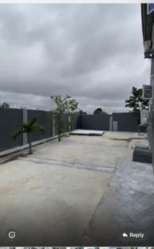 un aparcamiento con una valla y palmeras en EMKO House, en Ilorin
