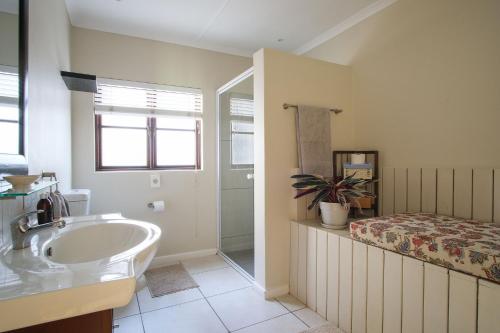 a bathroom with a sink and a bed at High Season Farm Luxury Cottages in Hermanus