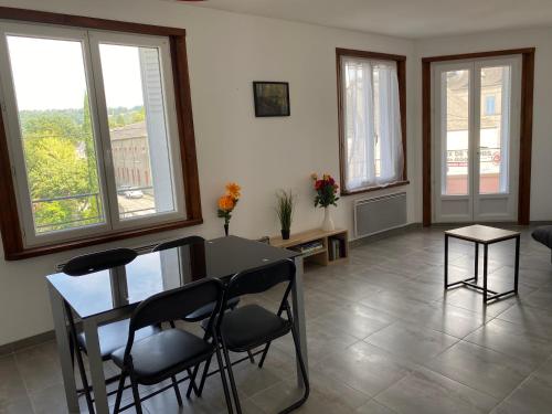 a living room with a table and chairs and windows at Appartement meublé 52m2 in Bagnères-de-Bigorre