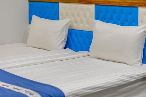 a bed with a blue headboard and white pillows at Sun Moon Lake Jinlongshan BnB in Yuchi
