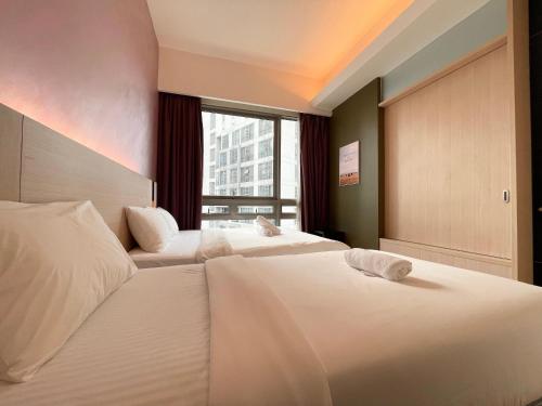 two beds in a hotel room with a window at Swiss Garden Residence by PILLOWTALKS in Kuala Lumpur
