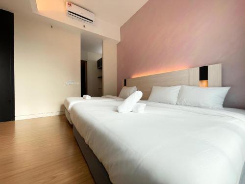 two beds in a hotel room with white sheets at Swiss Garden Residence by PILLOWTALKS in Kuala Lumpur